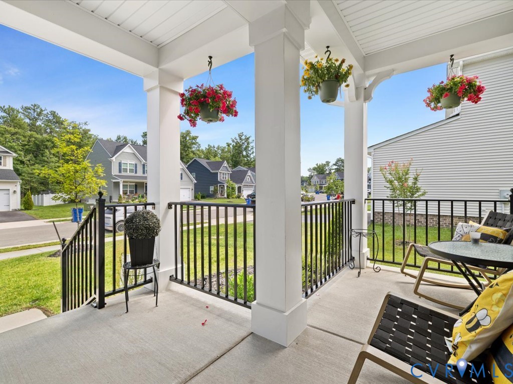 Expansive covered front porch with concrete flooring and black metal railings