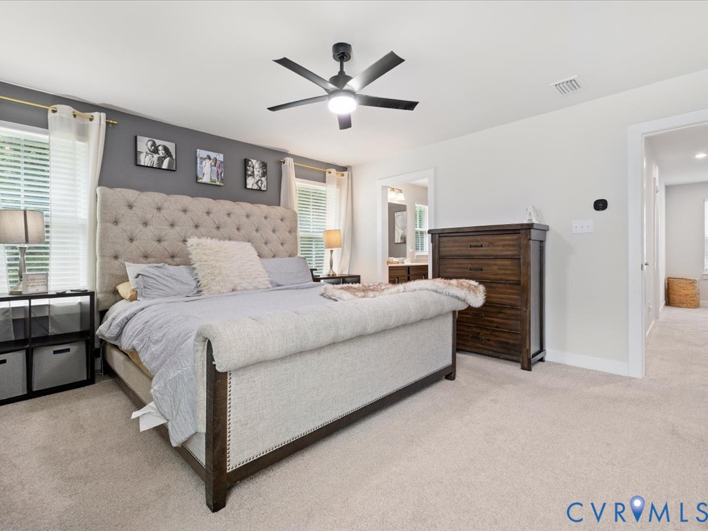 Plush carpeted flooring, neutral wall tones, and a ceiling fan with integrated lighting