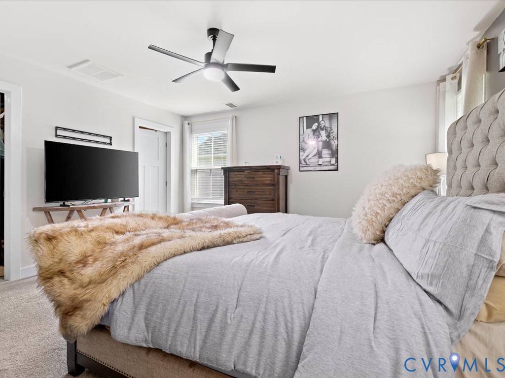 Ceiling fan with integrated lighting, window with blinds, light-colored walls, and neutral carpet flooring