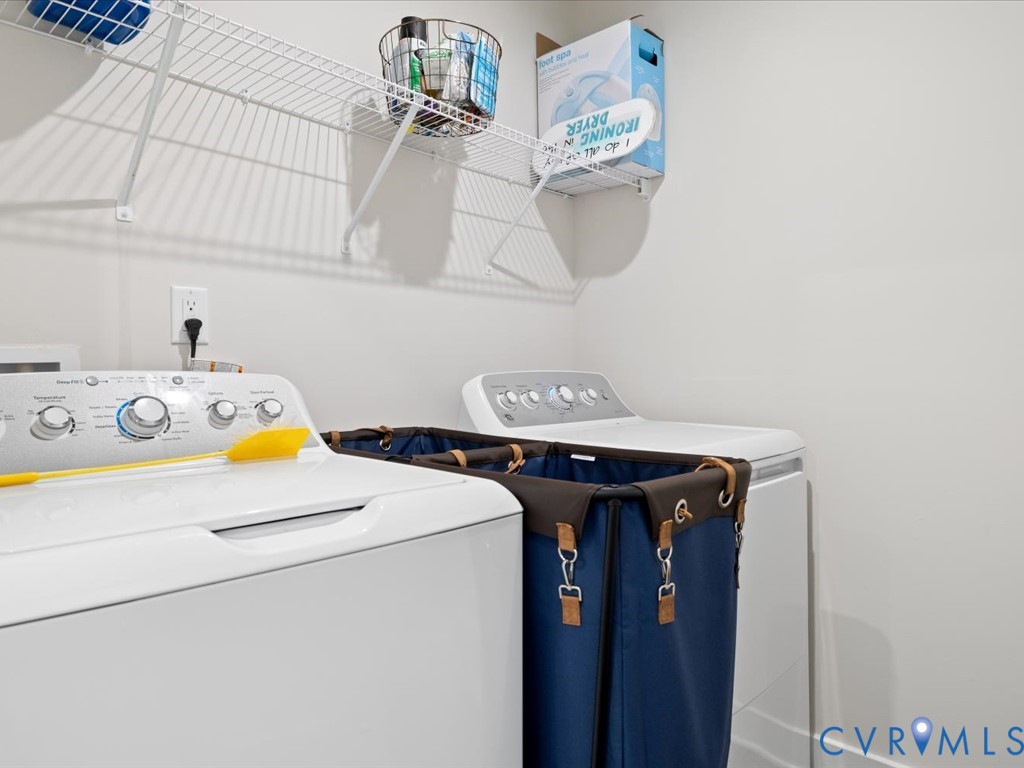 Utility area featuring two top-load washing machines and wall-mounted wire shelving