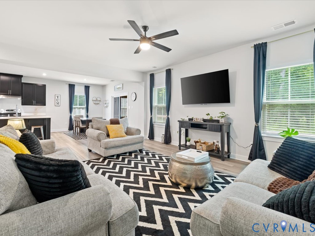 Open-concept living space with wood-finish flooring, a ceiling fan, and recessed lighting