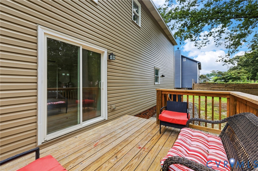 Spacious rear deck with wood railing, tan siding, and a white-framed sliding glass door