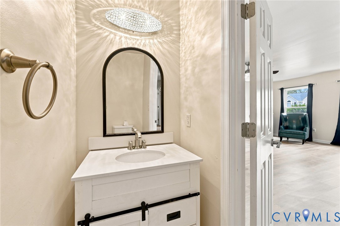 White vanity with black hardware, integrated sink, and an arched mirror