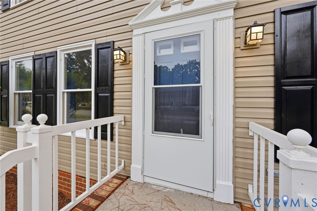 Welcoming entry featuring a white-trimmed glass and wood door with sidelights, flanked by white composite railings