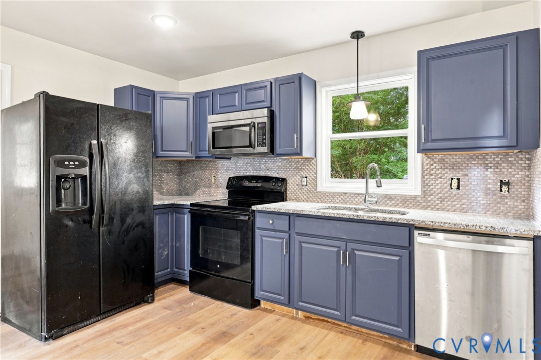 Kitchen featuring wood-finish flooring, blue cabinetry, granite countertops, a tiled backsplash, and stainless steel dishwasher