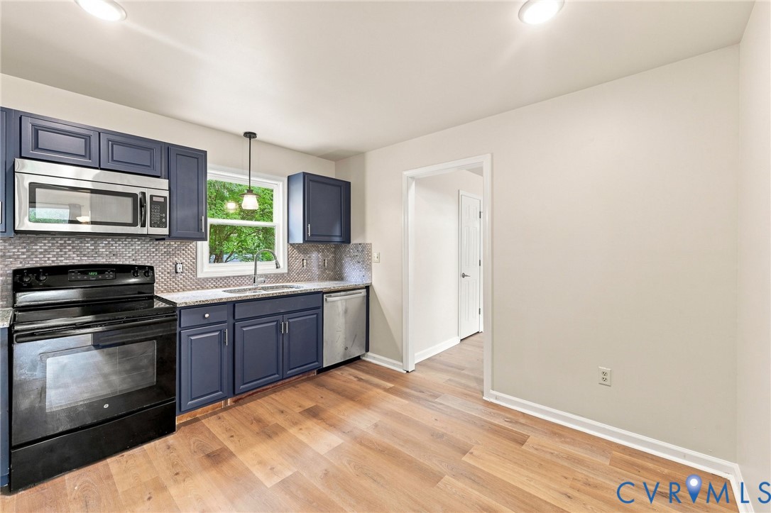 Kitchen featuring blue cabinetry, a stainless steel microwave, black electric range, and wood-finish flooring