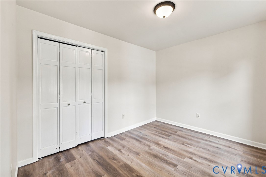 Crisp white walls, wood-finish flooring, white bi-fold closet doors, and a ceiling-mounted light fixture