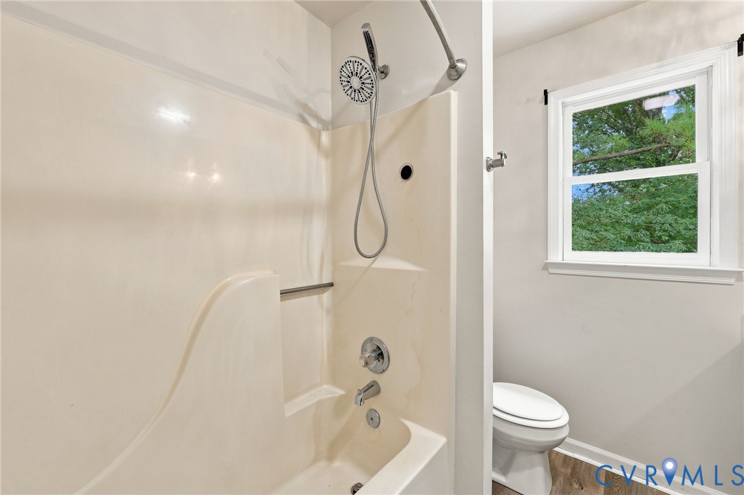 Bathtub shower combination with a handheld showerhead, chrome fixtures, and a built-in shower caddy