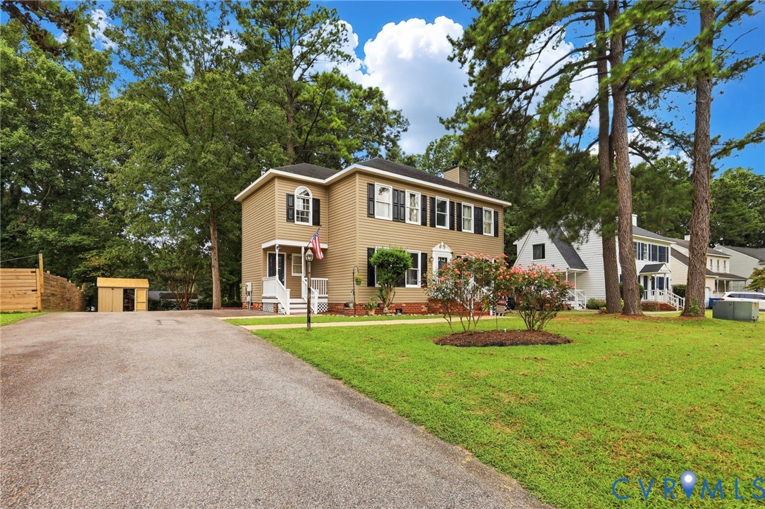 Two-story property with tan siding, black shutters, white trim, and a white front porch Two-story property with tan siding, black shutters, white trim, and a white front porch