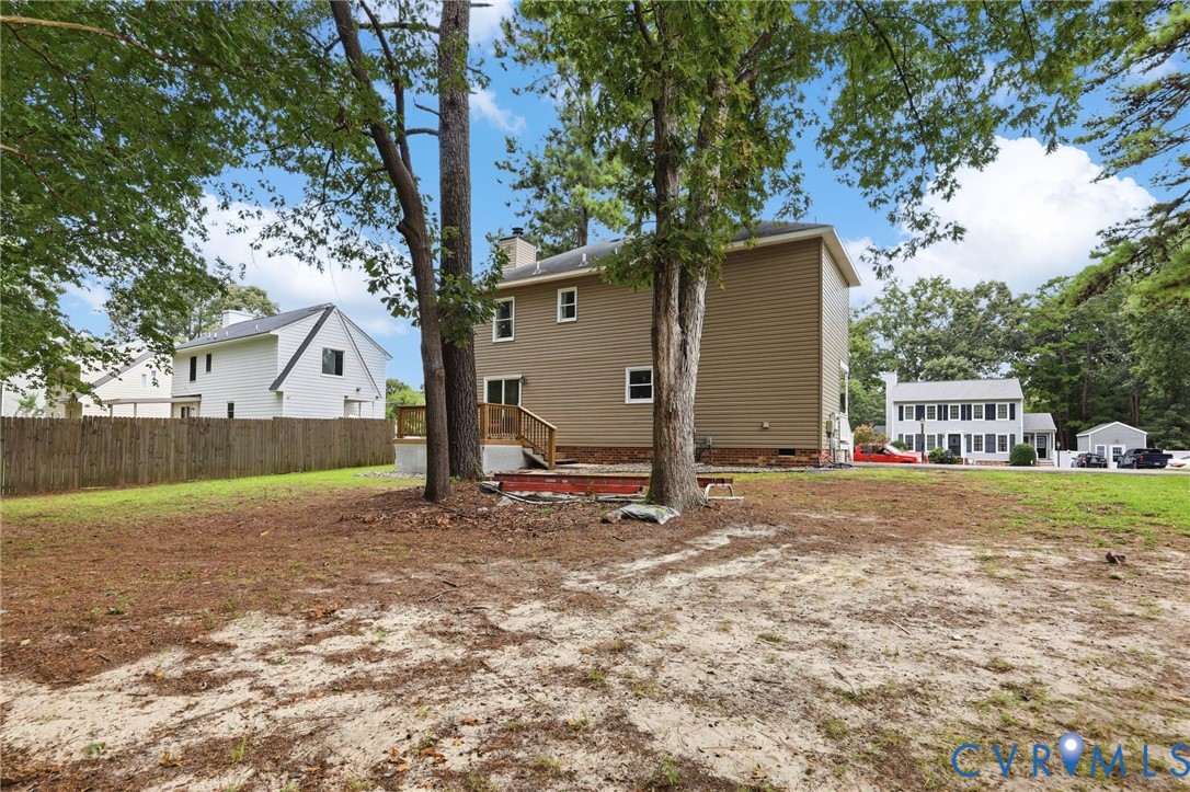 Expansive property with mature trees, a multi-level wood deck, and a privacy fence