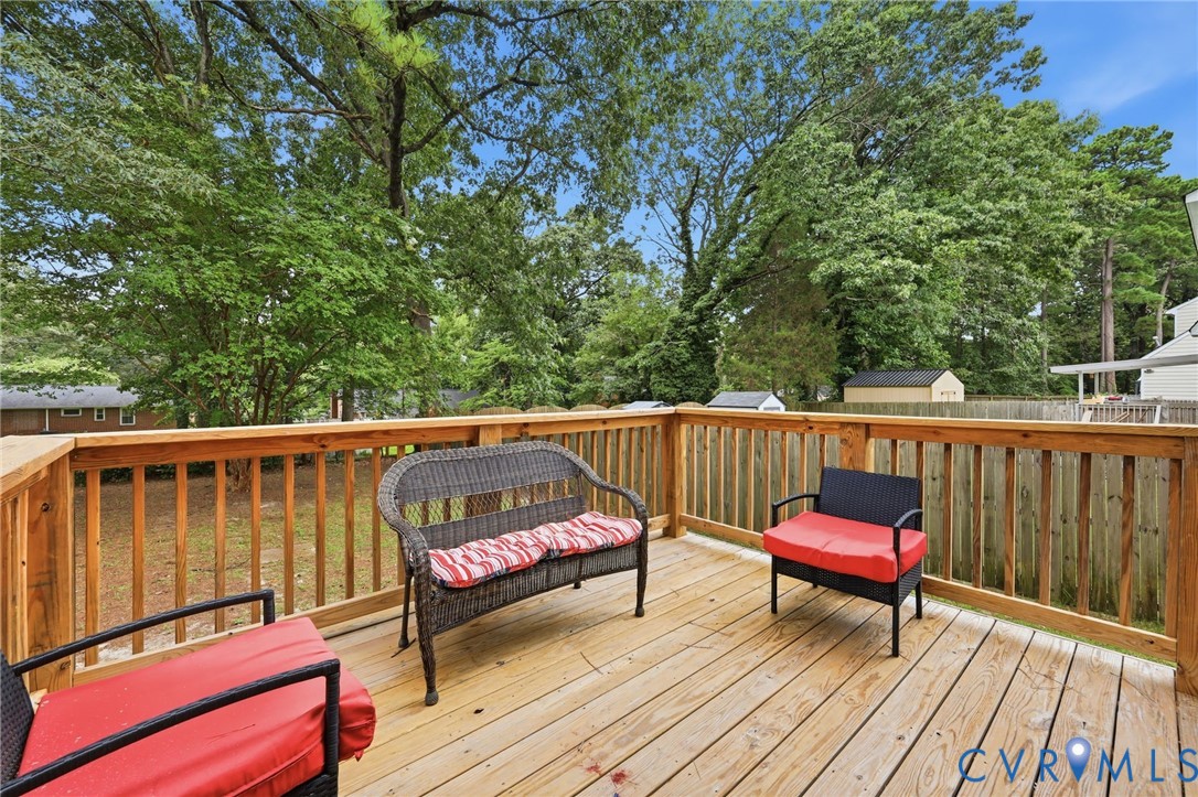 Expansive wood deck with a full wood railing overlooking a green yard and mature trees
