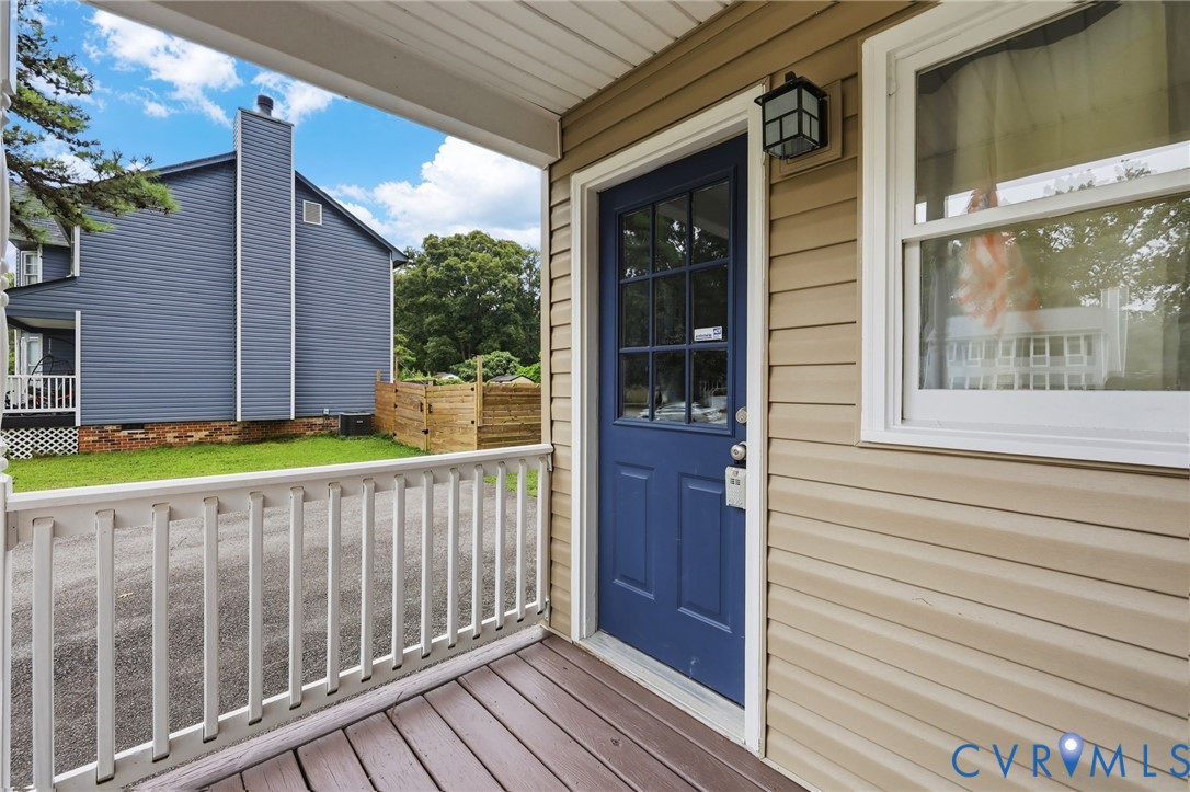 Covered porch with wood-finish decking, white railings, and a prominent blue entry door