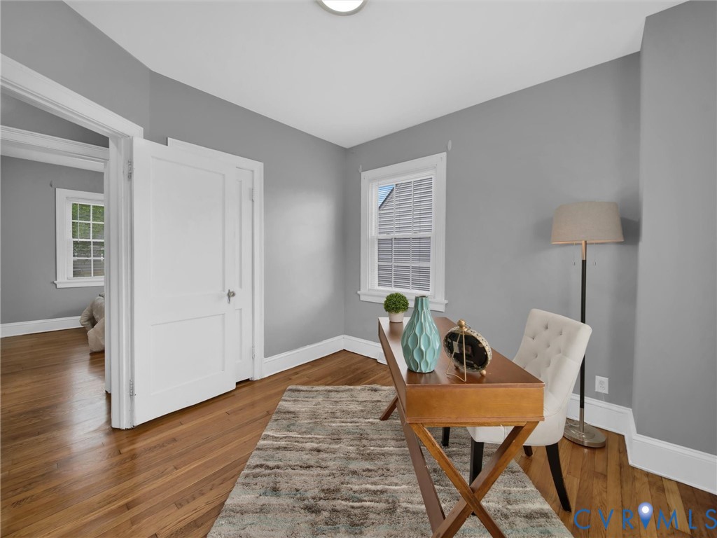 Room featuring wood-finish flooring, light grey painted walls, white trim, and a window with a white frame