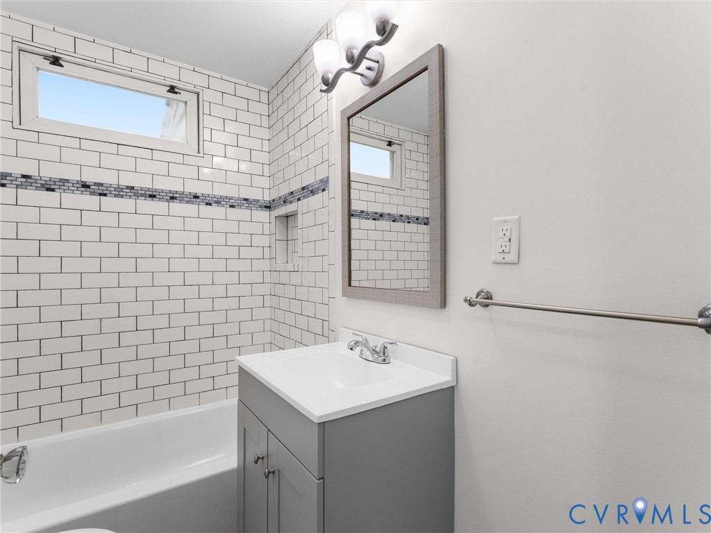 Bathroom featuring a white subway tile surround with a decorative mosaic accent band, a built-in shower niche, and an upper transom window