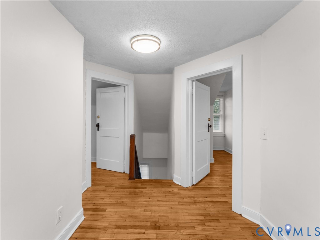 Hallway with natural wood flooring and multiple doorways