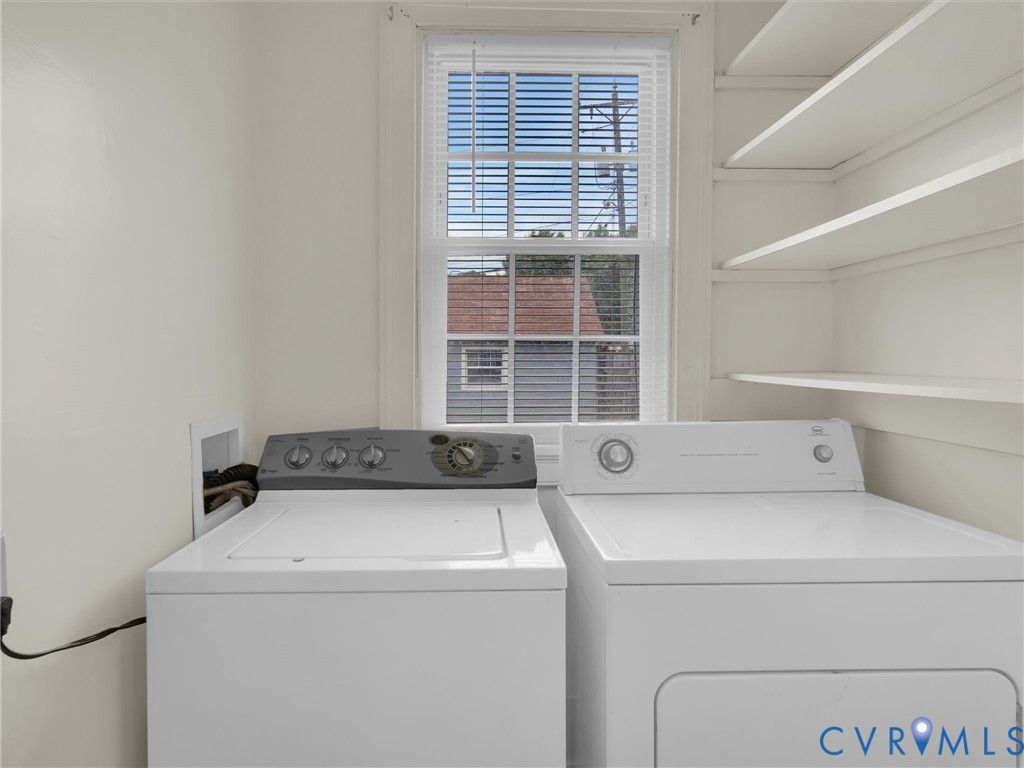 Dedicated laundry area featuring a washer and dryer, built-in shelving, and a window with blinds