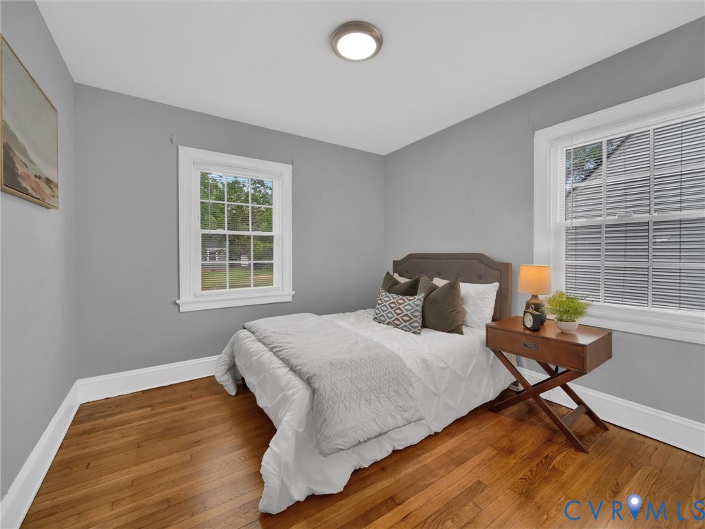 Room featuring wood-finish flooring, two windows with white trim, gray walls, and a flush-mount ceiling light