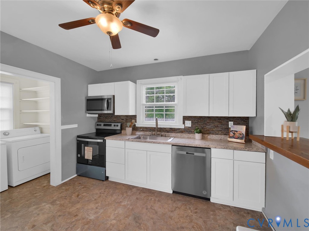 Kitchen featuring white cabinetry, stainless steel appliances, granite-style countertops, and mosaic tile backsplash