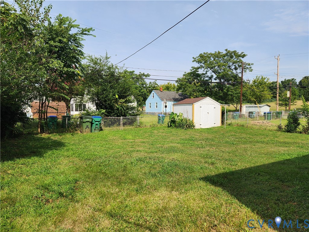 Expansive lawn area with a white storage shed and chain-link fencing