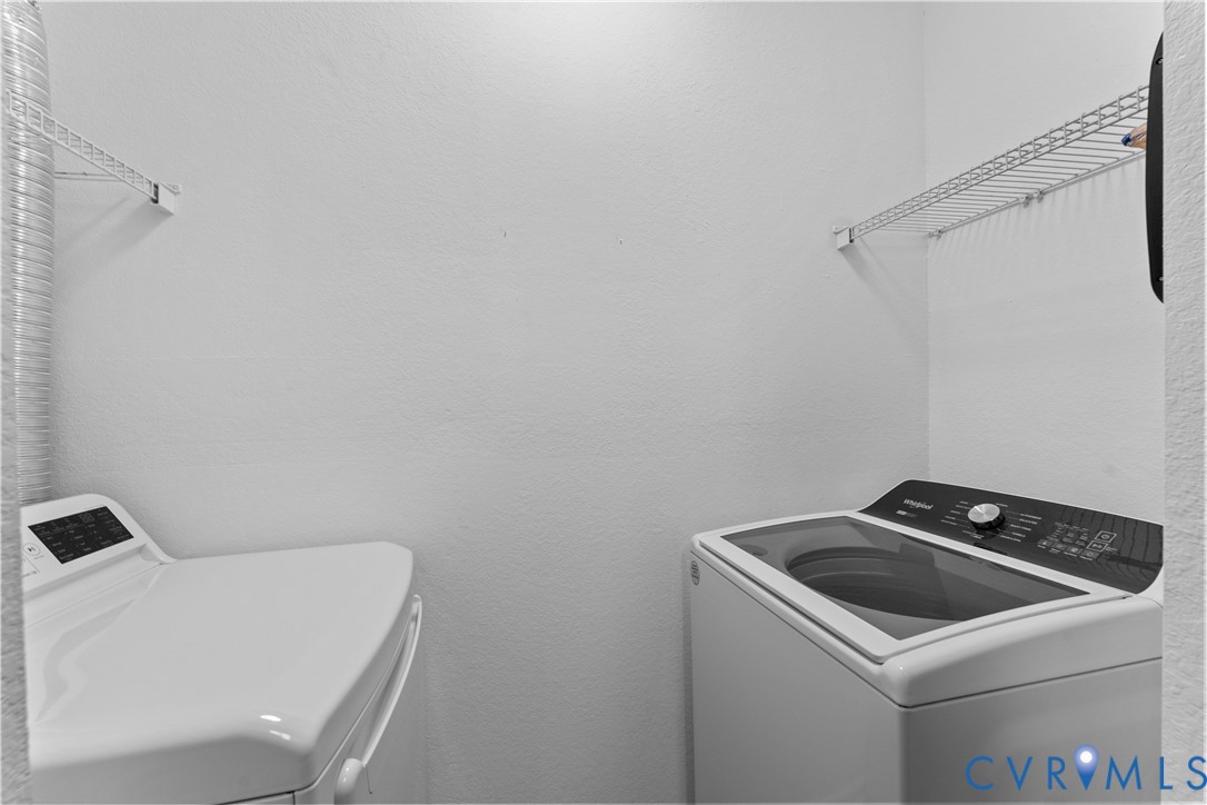 Laundry area featuring dual white wall-mounted wire shelving units and top-loading laundry appliances