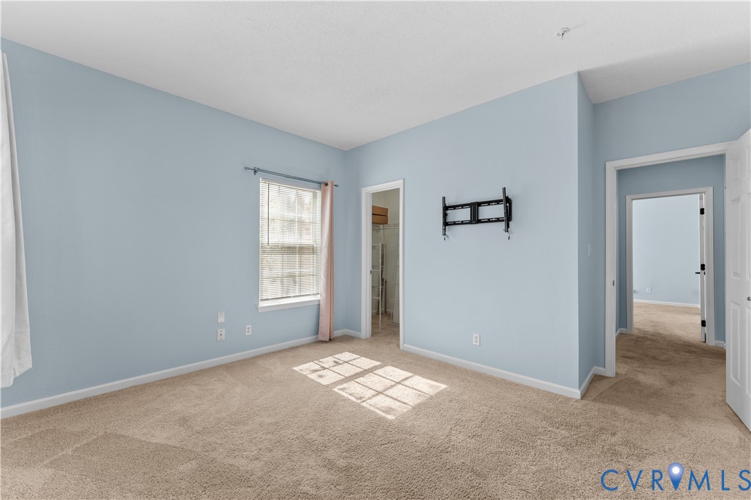 Light-filled room featuring wall-to-wall carpeting, a single-hung window with a neutral finish, and an integrated walk-in closet
