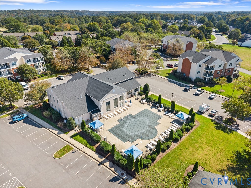 Aerial perspective featuring an outdoor swimming pool, paved surface decking, designated parking area, and manicured landscaping