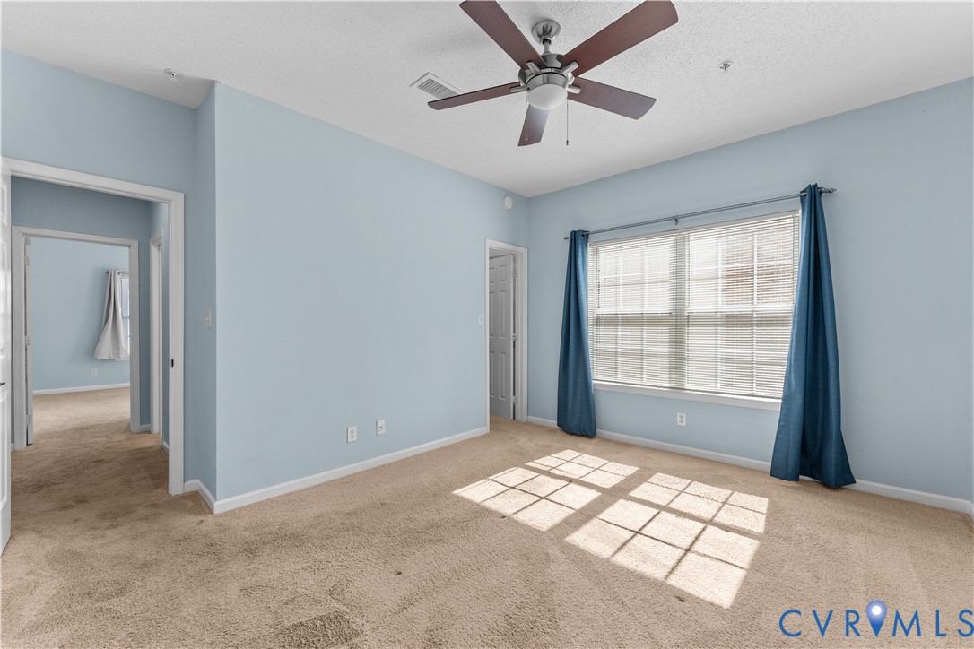 Carpeted room featuring a ceiling fan with integrated lighting, dual-pane window, and light-toned wall finish