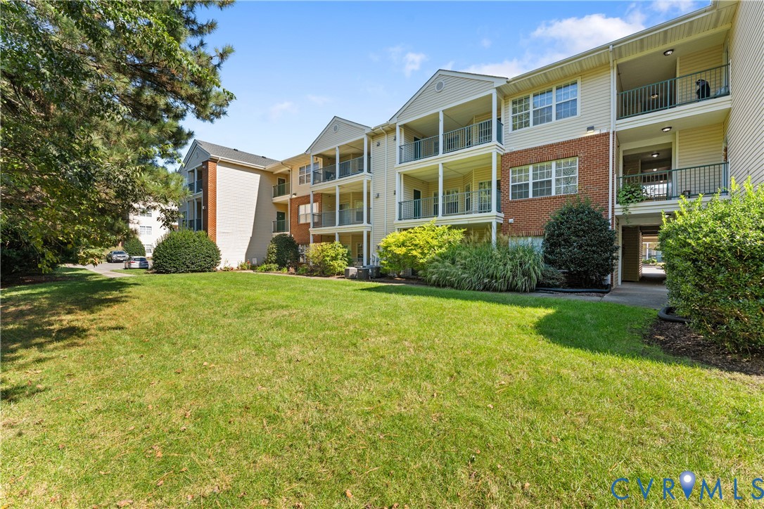 Exterior featuring brick and siding facade, covered balconies, and landscaped grounds