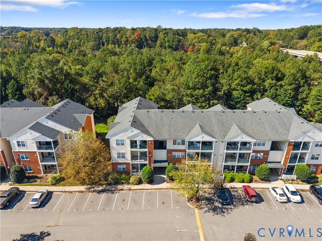Multi-story complex featuring brick and siding facade, gabled rooflines, covered balconies, and dedicated asphalt parking
