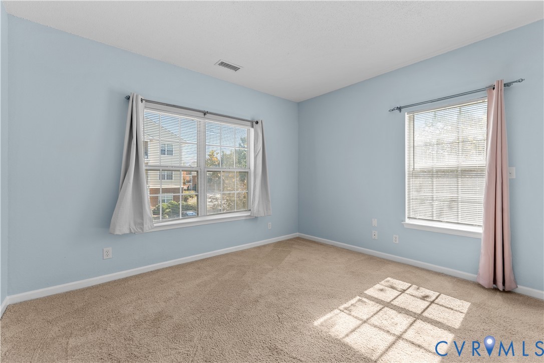Interior room featuring neutral-toned carpeting, two windows with grid-patterned muntins, and ample natural light