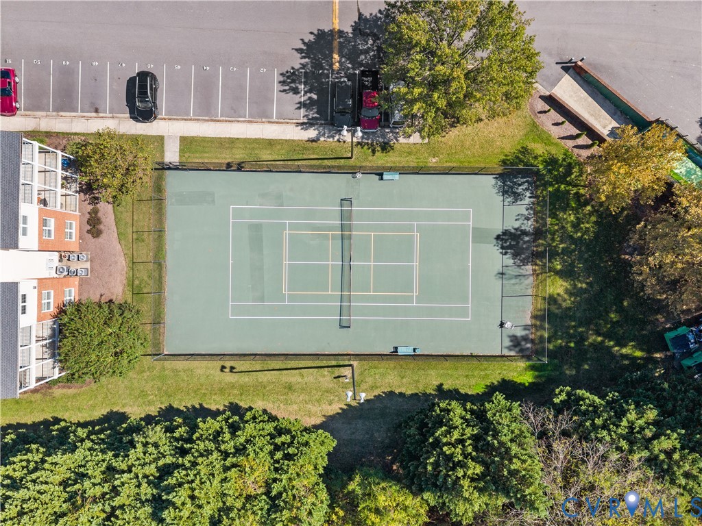 Tennis court featuring a paved surface, perimeter chain-link fencing, net, and ground-mounted lighting
