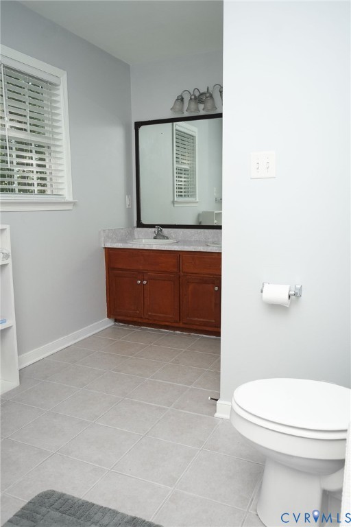 Vanity with wood-finish cabinetry, light-toned countertop, and mirror with an overhead light fixture
