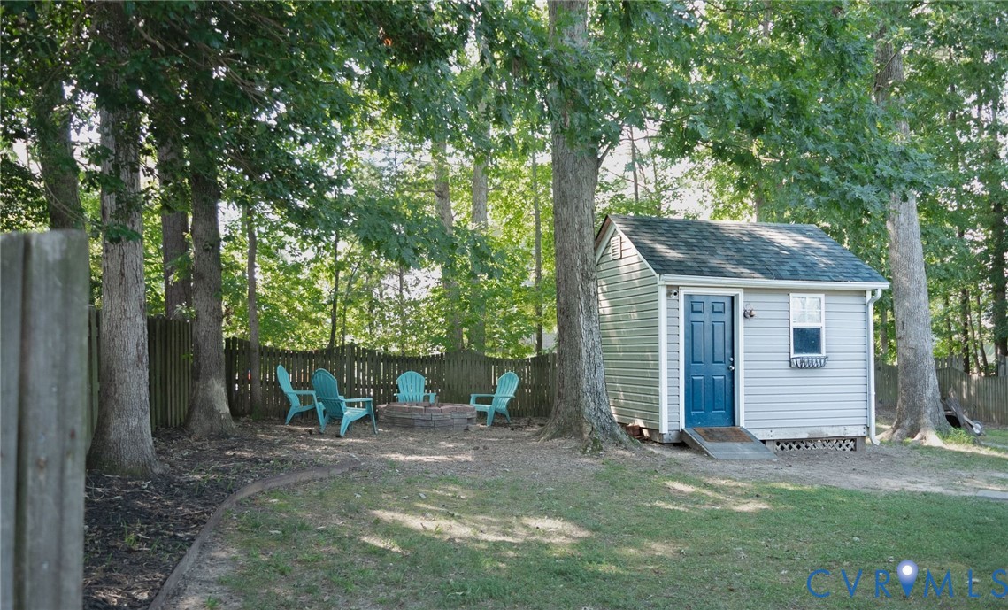 Detached storage shed with blue door and ramp access, surrounded by mature trees Detached storage shed with blue door and ramp access, surrounded by mature trees