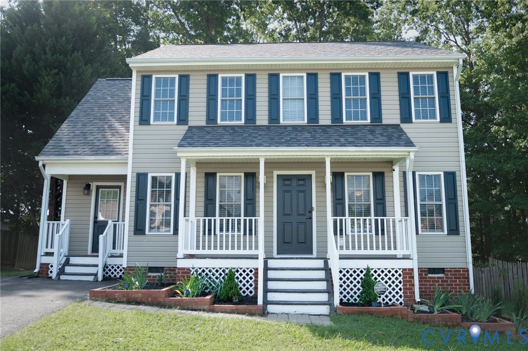Traditional two-story exterior featuring tan siding, a dark shingle roof, and white-railed front porches Traditional two-story exterior featuring tan siding, a dark shingle roof, and white-railed front porches