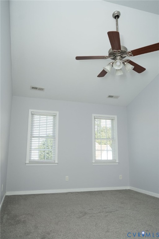 Vaulted ceiling, ceiling fan with integrated lighting, two windows with blinds, gray wall paint, and gray carpeting