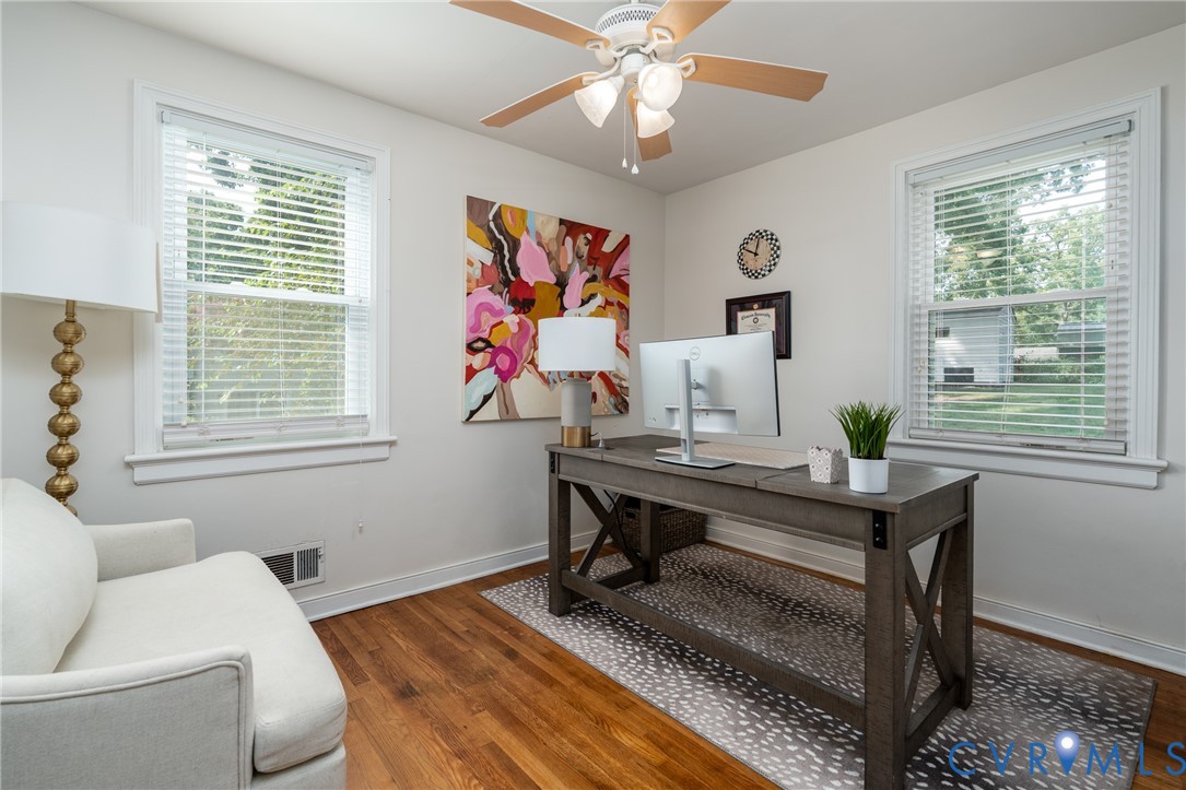 Hardwood flooring, painted walls, ceiling fan with integrated lighting, and two windows with blinds