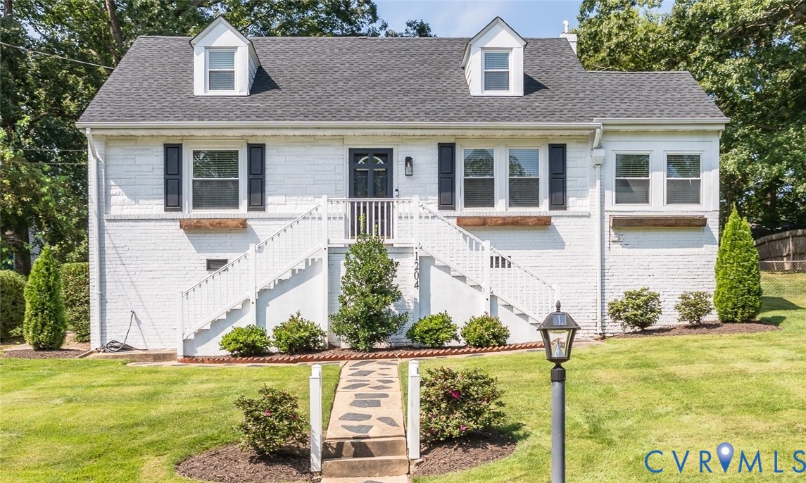 White brick exterior with a dark shingle roof and dormer windows White brick exterior with a dark shingle roof and dormer windows