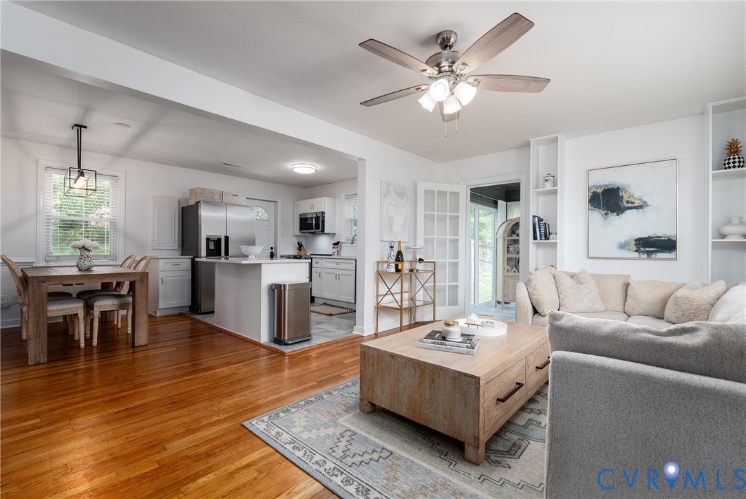 Hardwood flooring, stainless steel appliances, white cabinetry, built-in shelving, and French doors