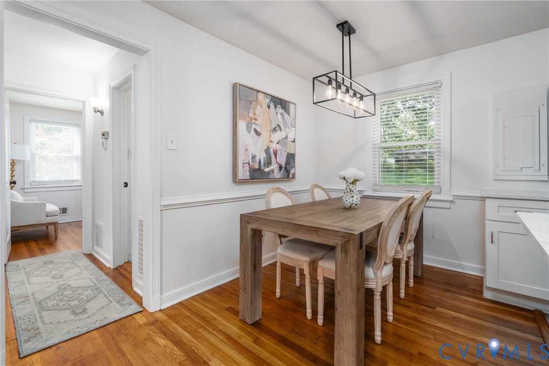 Hardwood flooring, painted white walls, picture rail molding, and a modern rectangular chandelier