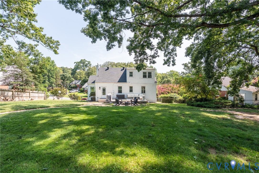 Expansive grassy yard with mature trees and a fenced perimeter