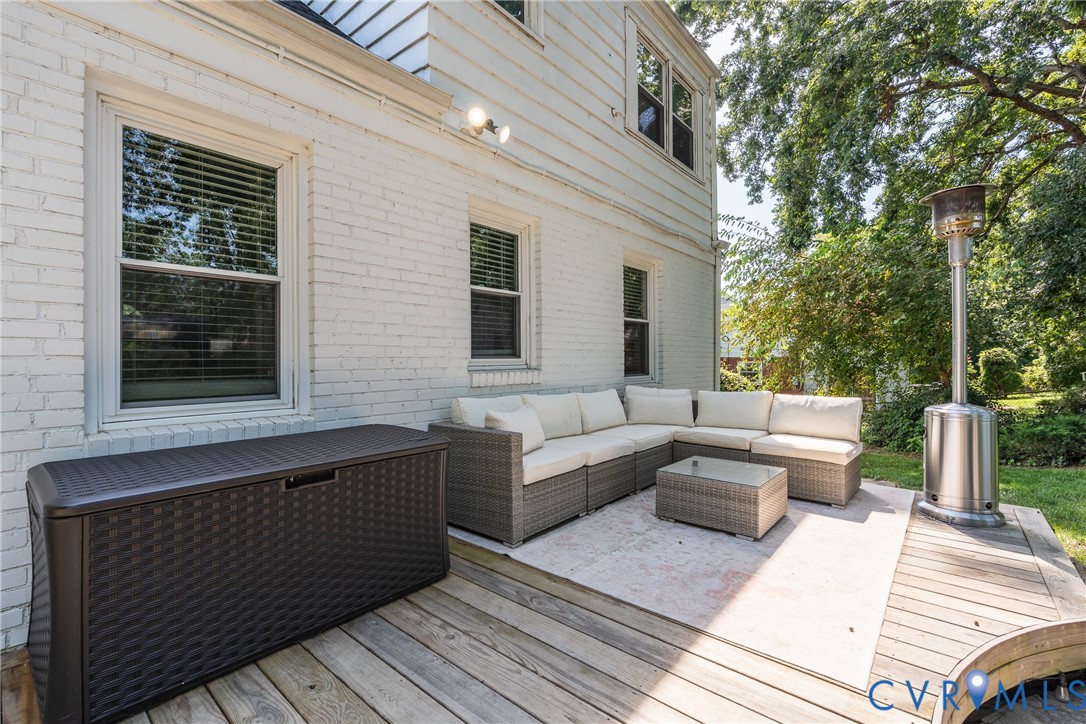 White brick exterior with dual windows, wood deck, and concrete patio