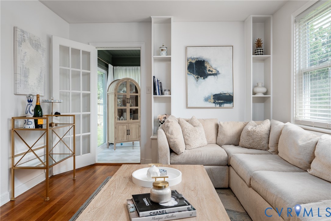 Hardwood flooring, French doors, built-in shelving, white window blinds, and white walls