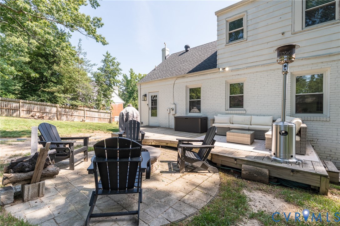 Expansive backyard featuring a raised wooden deck, a secondary stone patio, and perimeter fencing