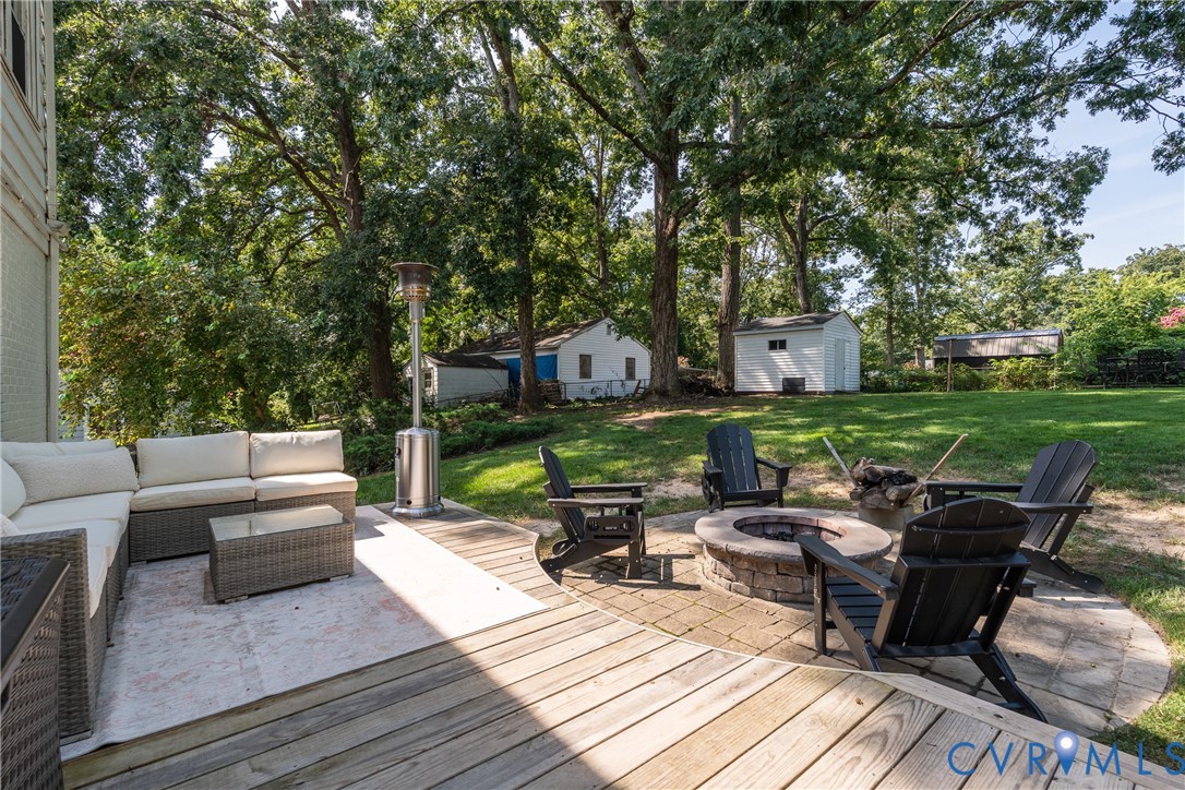 Expansive backyard featuring a stone fire pit, wood deck, and a detached storage shed