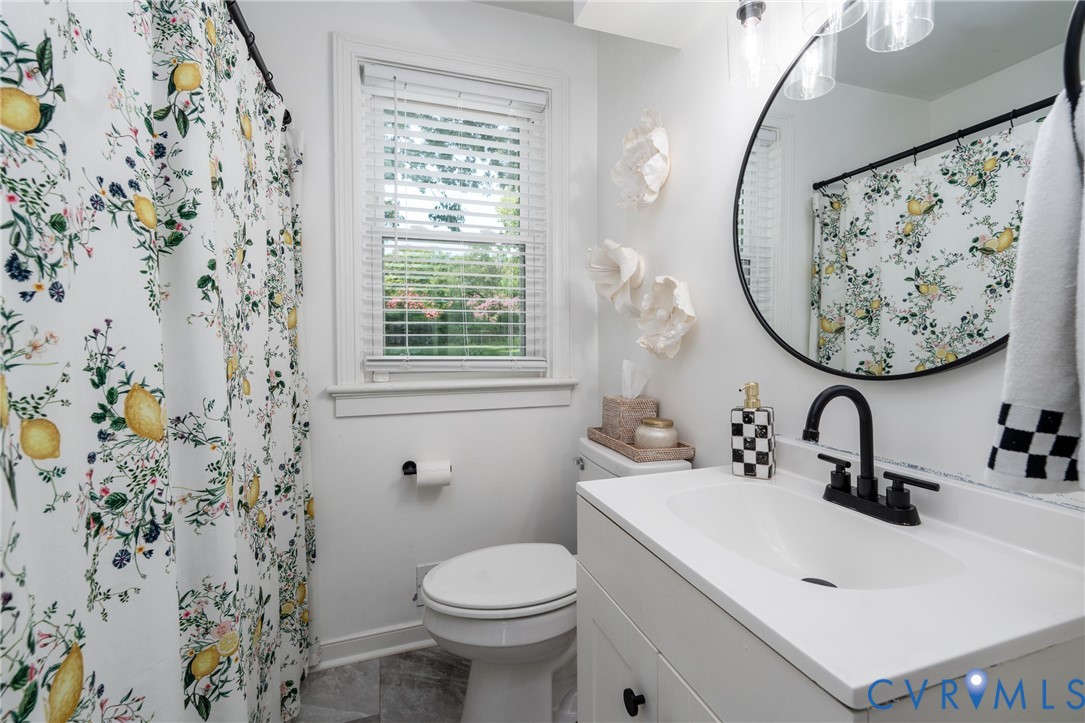 White vanity with an integrated sink and matte black faucet, illuminated by a three-light fixture