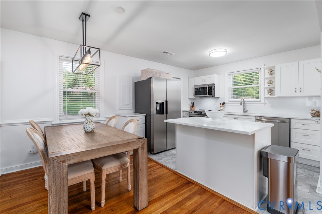 Kitchen featuring stainless steel appliances, white cabinetry, a central island, and a tile backsplash