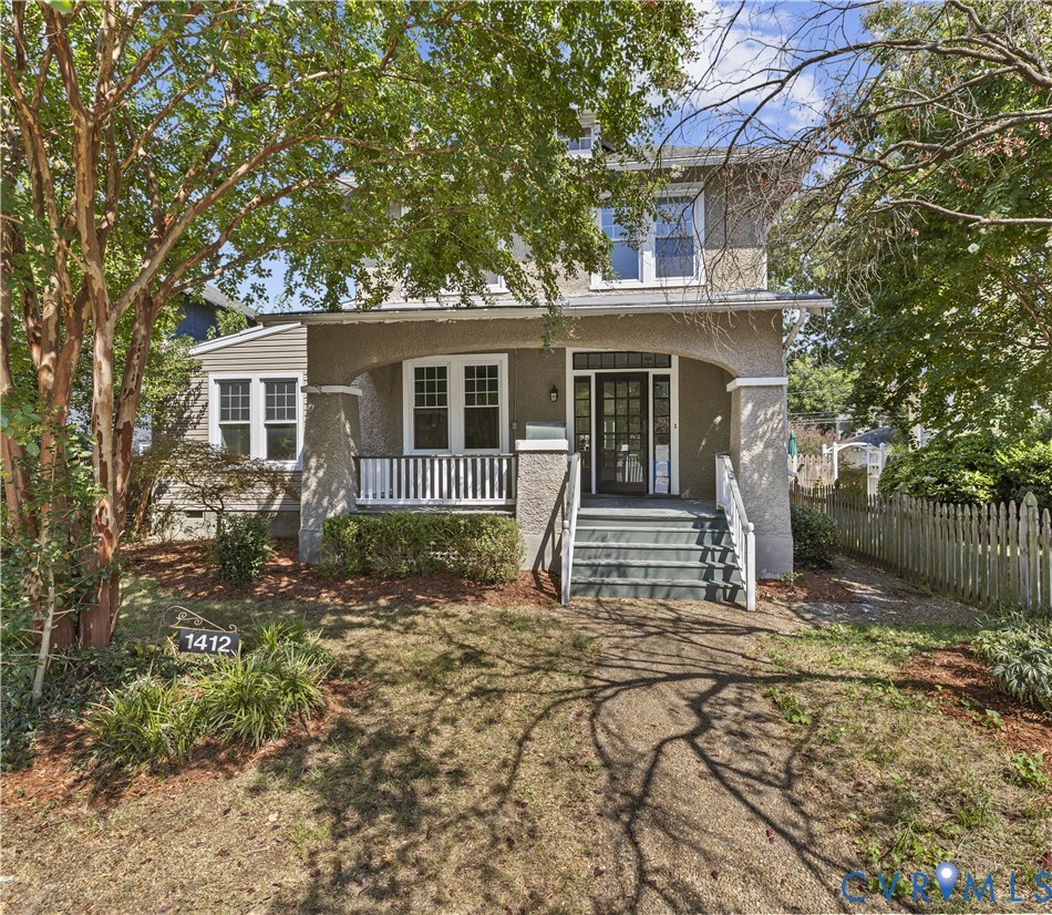 Stucco exterior with a covered front porch, white railing, and exterior staircase Stucco exterior with a covered front porch, white railing, and exterior staircase