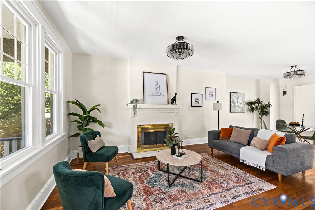 Hardwood flooring, white window frames, recessed fireplace with brass surround, white mantel, and two ceiling-mounted light fixtures Hardwood flooring, white window frames, recessed fireplace with brass surround, white mantel, and two ceiling-mounted light fixtures