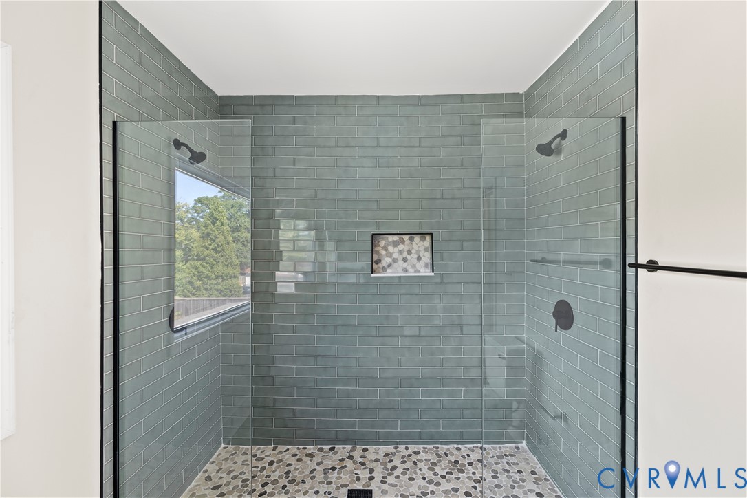 Walk-in shower with full-height glass enclosure, subway tile walls, dual shower heads, and an integrated niche
