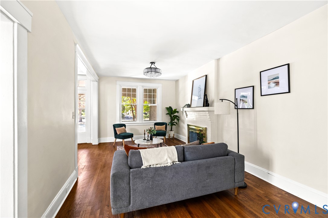 Hardwood flooring, a decorative fireplace, large windows, and a semi-flush mount ceiling fixture Hardwood flooring, a decorative fireplace, large windows, and a semi-flush mount ceiling fixture